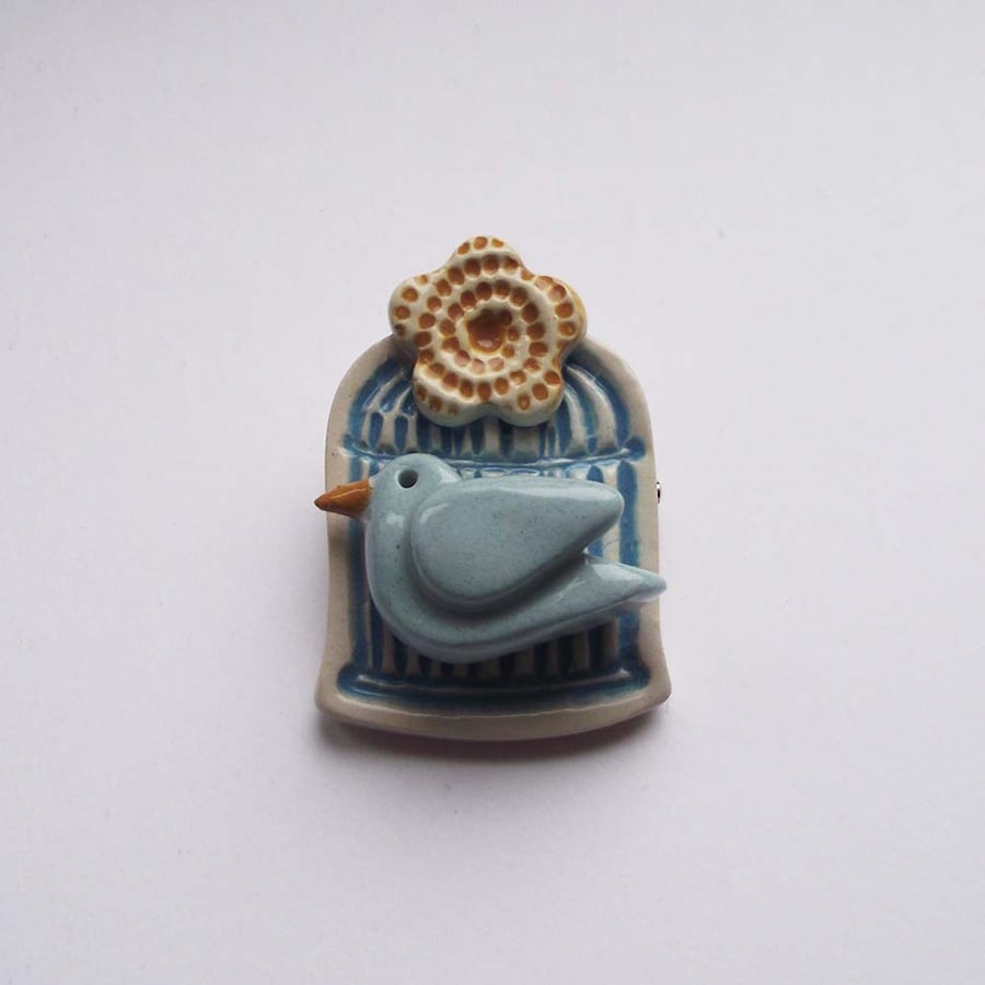 Little ceramic bird cage brooch with flower. Pottery jewellery