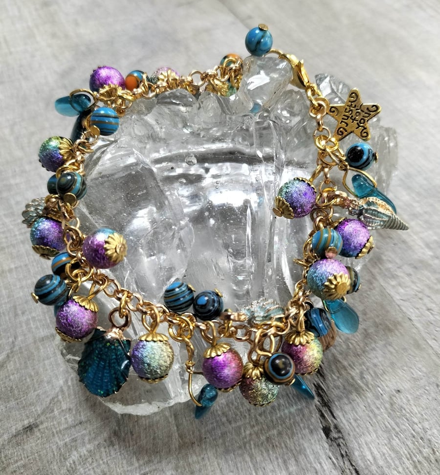 Gold tone purple miracle bead bracelet with shell charms