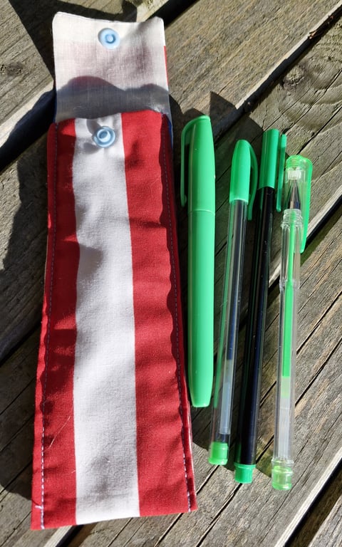 Red white and blue striped  pen case with 4 green pens.