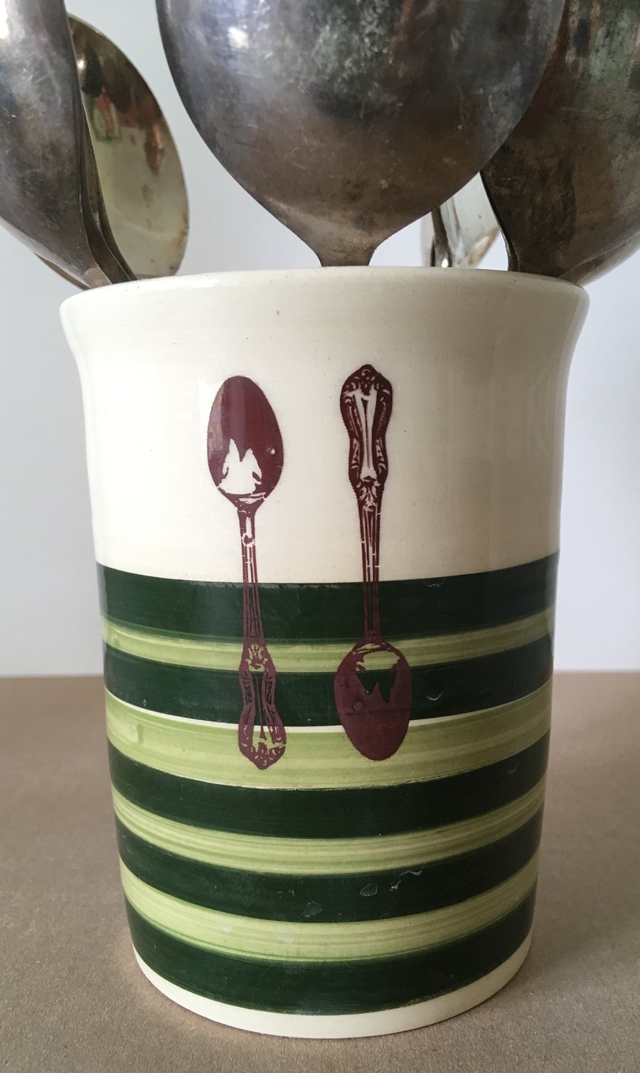 Ceramic cutlery pot with green stripes.