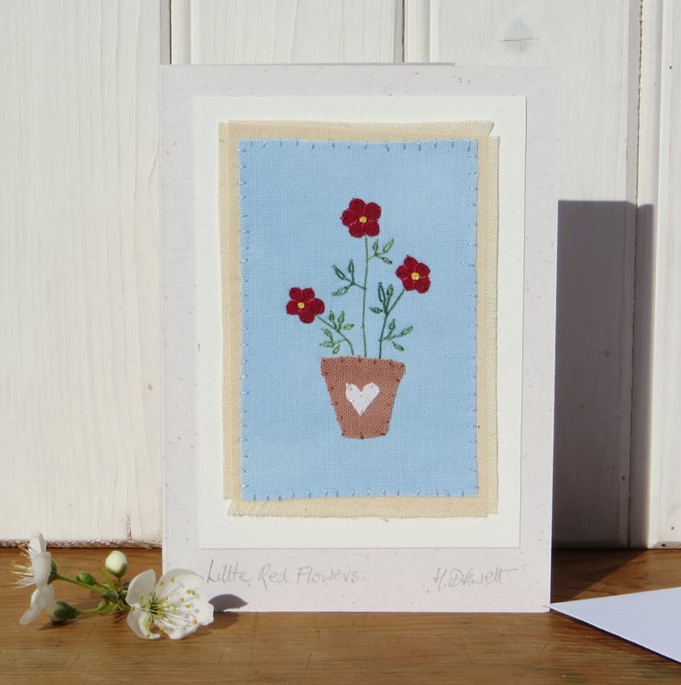 Hand-stitched applique red flowers in a pot with embroidered leaves 