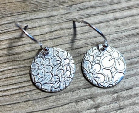 Circular silver earrings with embossed flower pattern