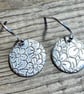 Circular silver earrings with embossed flower pattern