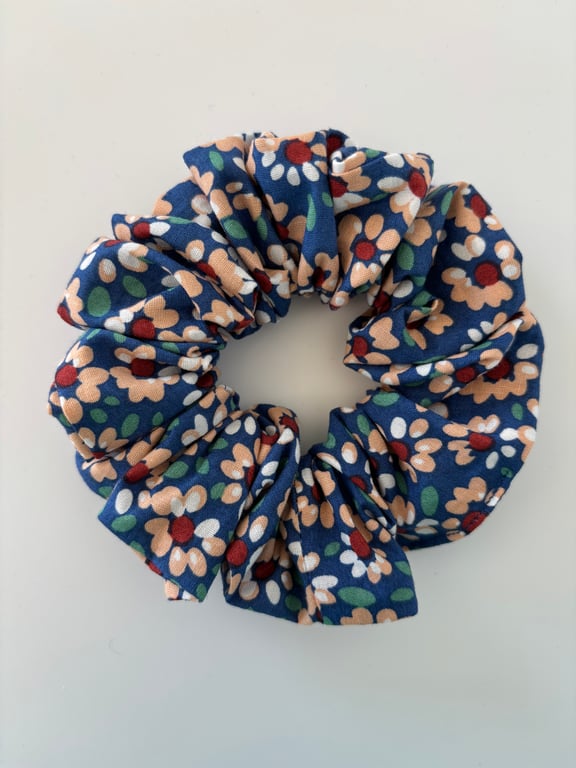 Cotton scrunchie hair accessory in a daisy floral print on blue background