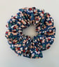 Cotton scrunchie hair accessory in a daisy floral print on blue background