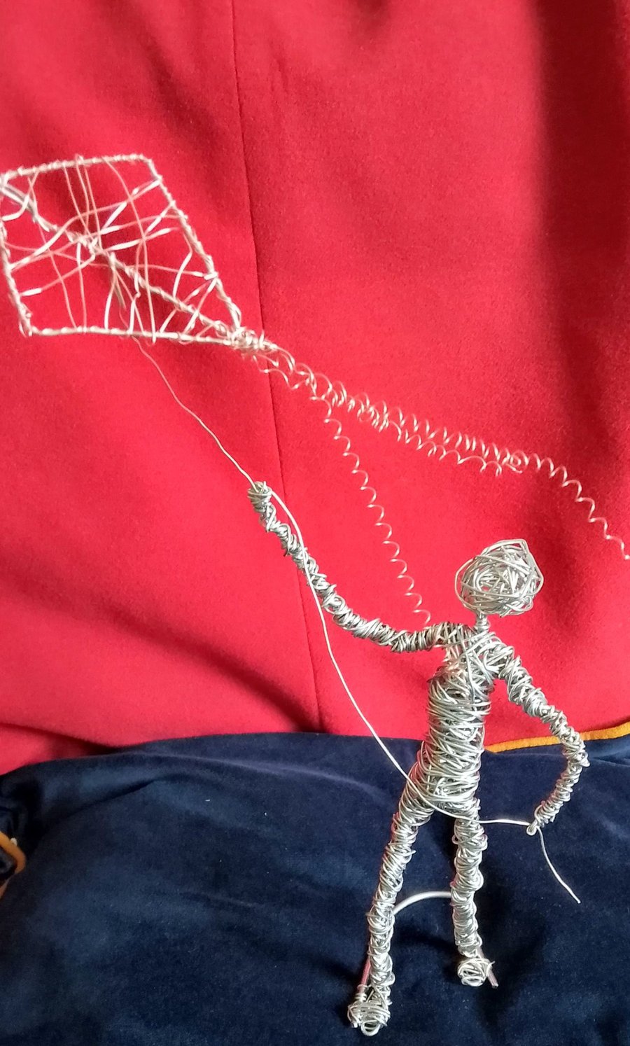 figure made out of wire flying a kite 