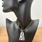 Handmade porcelain pendant in orange and blue on a green cord necklace