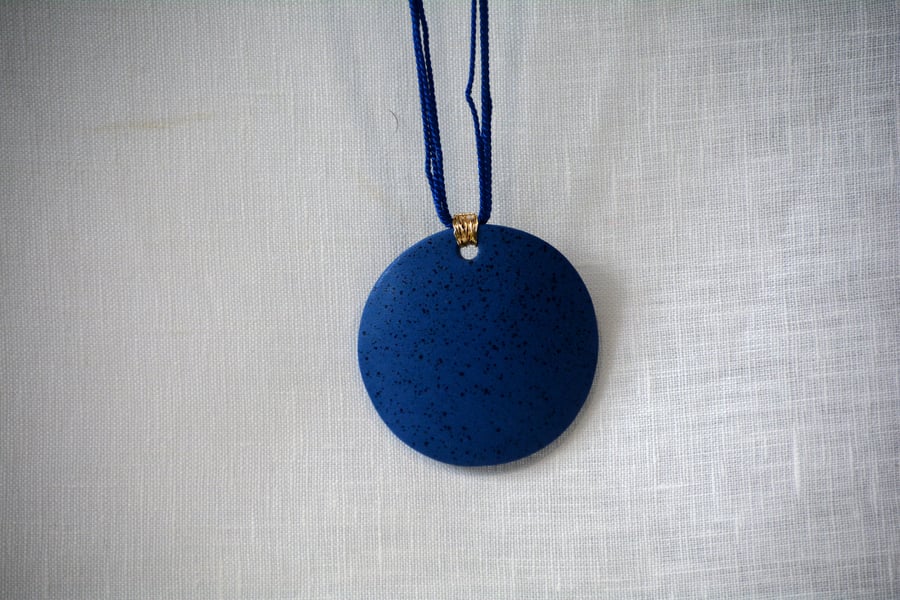 Speckled blue porcelain pendant with gold colour plated wire 