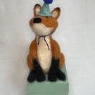 Handcrafted needle felted fox with removable party hat on a wooden box