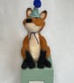 Handcrafted needle felted fox with removable party hat on a wooden box