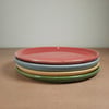 A set of six coloured ceramic side plates, cheese plates