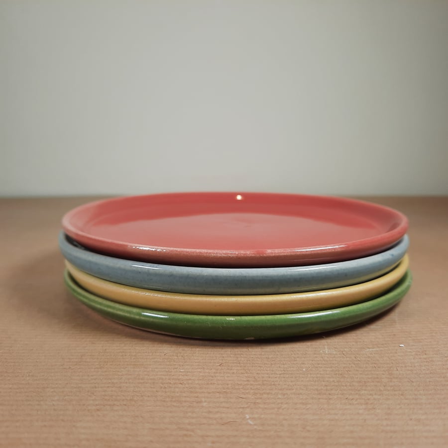 A set of four coloured ceramic side plates, cheese plates