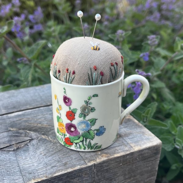 Pincushion in a vintage coffee cup with hollyhocks