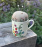 Pincushion in a vintage coffee cup with hollyhocks