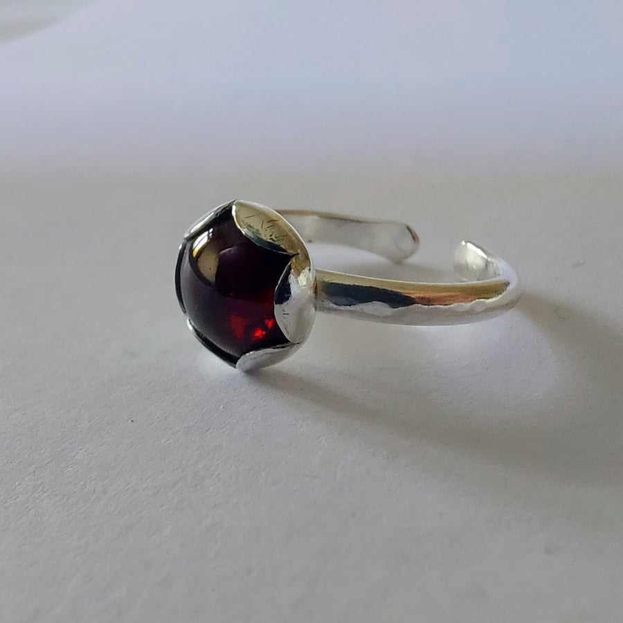 Adjustable sterling silver ring with garnet in petal setting. 