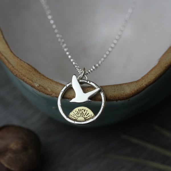 Small sterling silver flying bird necklace with brass sun