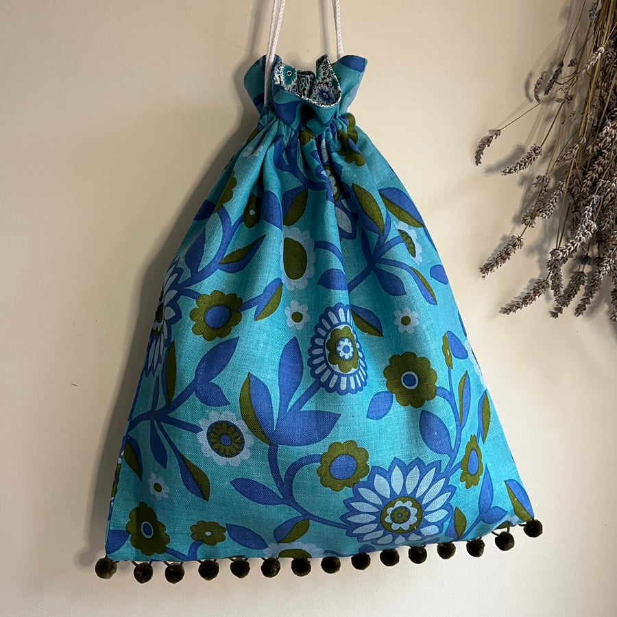 Bright blue vintage linen drawstring bag with pompoms and floral cotton lining
