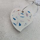 A handmade jesmonite heart filled with multicoloured hand dyed aluminium pieces