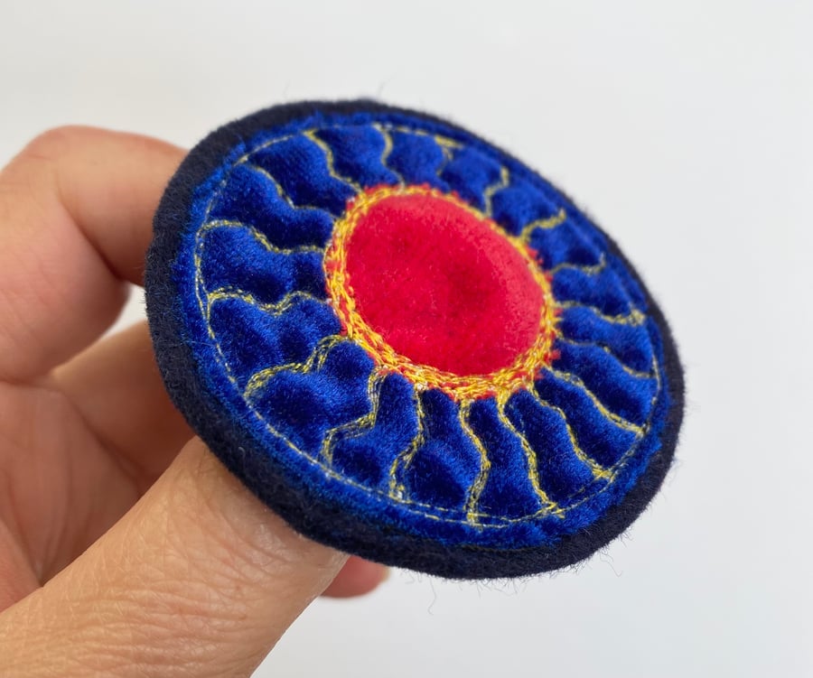Embroidered circular sun brooch pin of badge. 