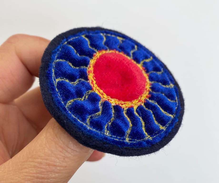 Embroidered circular sun brooch pin of badge. 