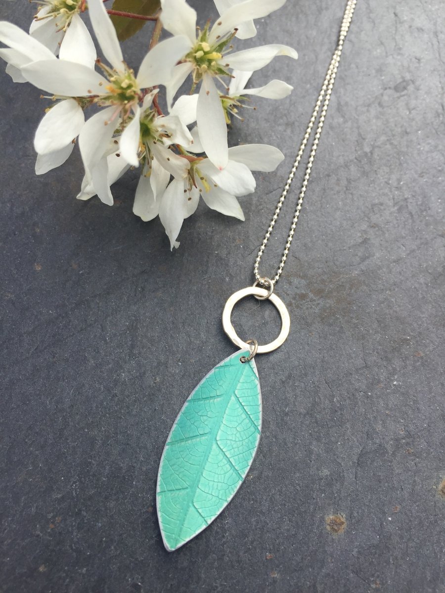 Soft green, anodised aluminium distressed leaf pendant with silver ring.