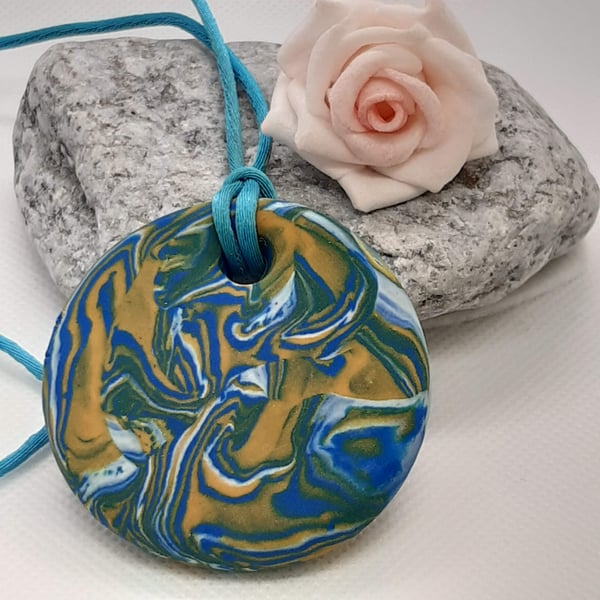 Round pendant in a turquoise, yellow and white polymer clay mix