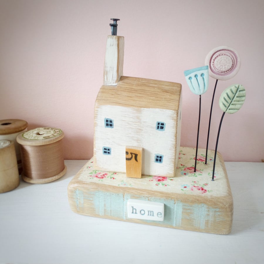 Wooden house on oak block with clay flowers 'home'