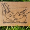 Hand printed signed linocut card "two's company" of 2 rabbits.