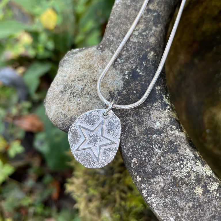 A freeform silver pendant with star on a sterling chain