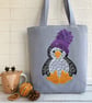 Penguin tote bag in pale blue with a paisley penguin in a purple bobble hat - Image 1