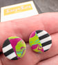 Stud earrings featuring monochrome strips and hot pink marble effect