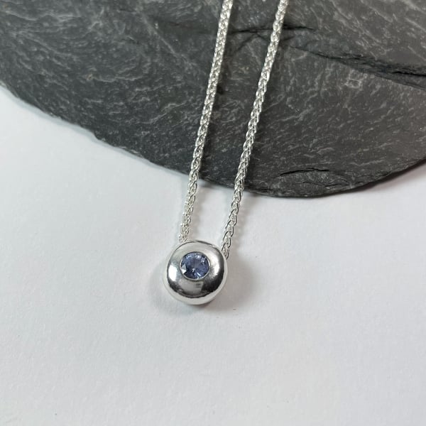 Simple silver nugget pendant on chain set with light blue sapphire