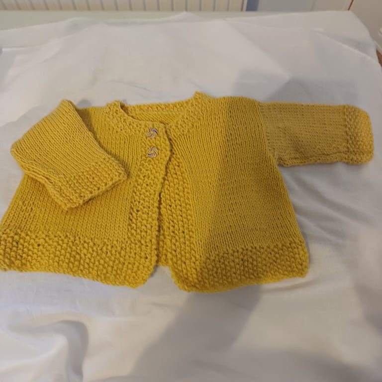 Handknit baby cardigan in a golden yellow 100% wool yarn.