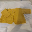 Handknit baby cardigan in a golden yellow 100% wool yarn.