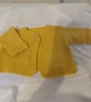 Handknit baby cardigan in a golden yellow 100% wool yarn.