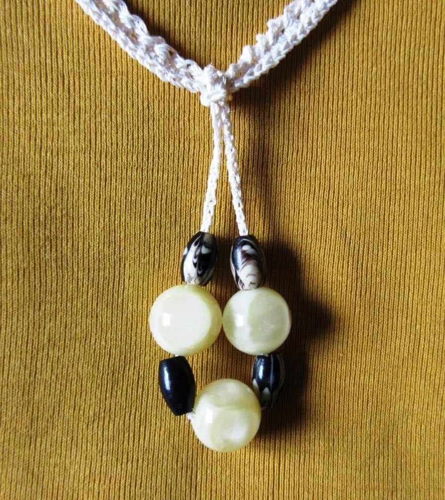 A crocheted necklace comprising a crocheted chain with a looped drop of beads