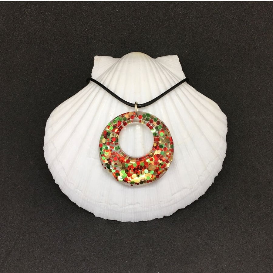Red green and gold sparkly donut necklace encased in resin.