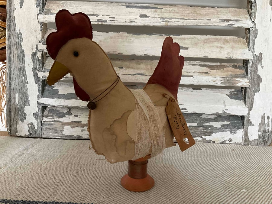 A charming primitive handmade hen on a vintage wooden spool