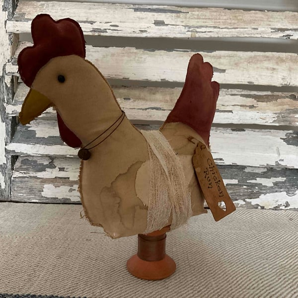 A charming primitive handmade hen on a vintage wooden spool