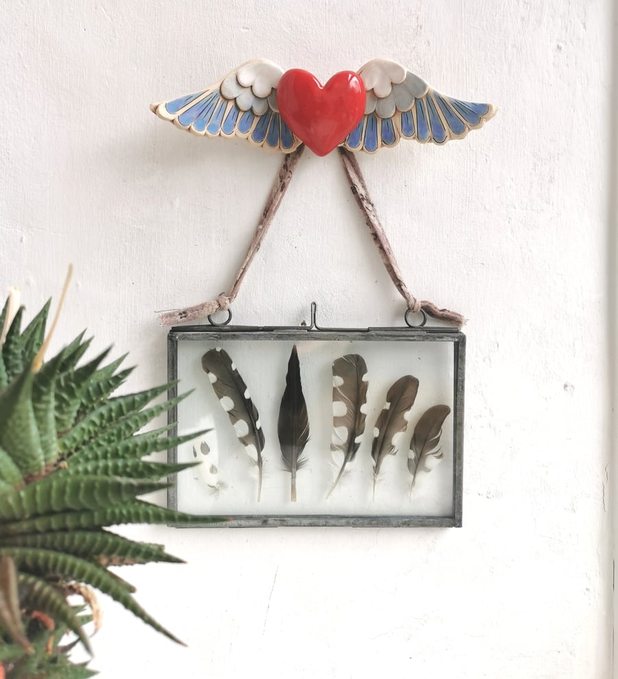 Ceramic winged heart wall art with red glazed heart and blue and white feathers
