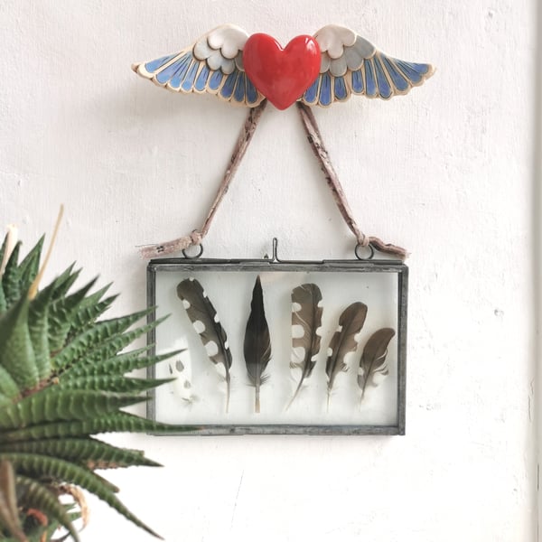 Ceramic winged heart wall art with red glazed heart and blue and white feathers