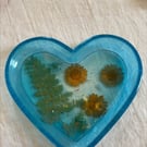 Flowery heart shaped epoxy resin trinket tray inlaid with dried flowers.