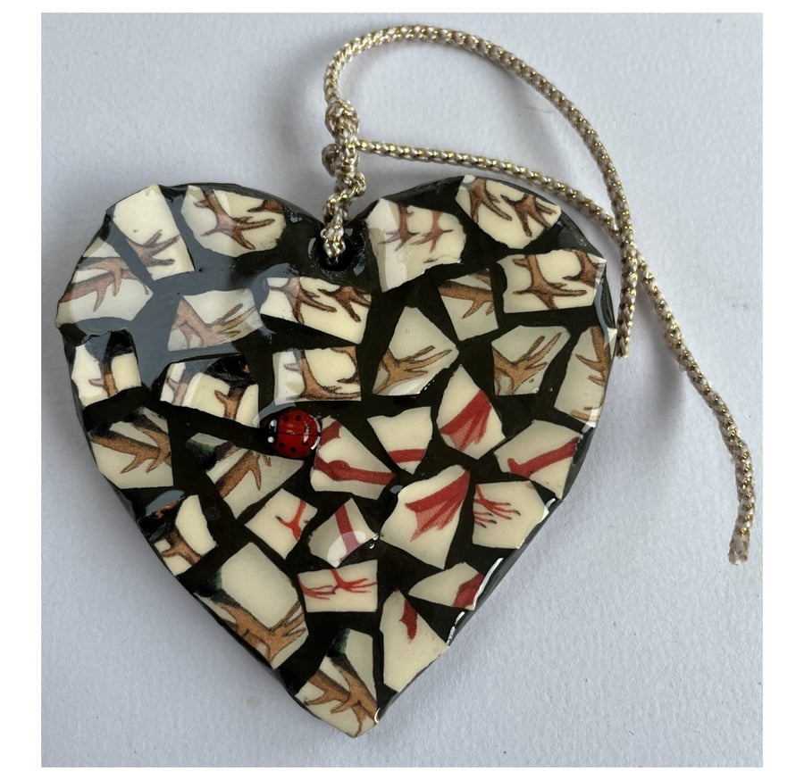 A heart shaped mosaic pendant with a sylised brown and red birds' feet theme.
