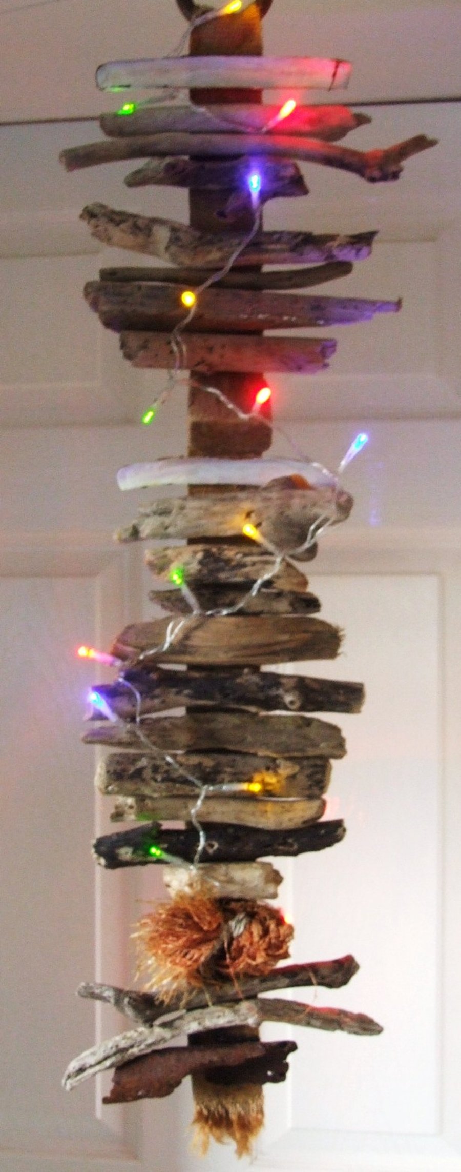 Illuminated driftwood wallhanging decoration with curling ribbon for Christmas