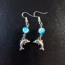 Silver dolphin charm dangle earrings with blue bead detail