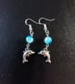 Silver dolphin charm dangle earrings with blue bead detail