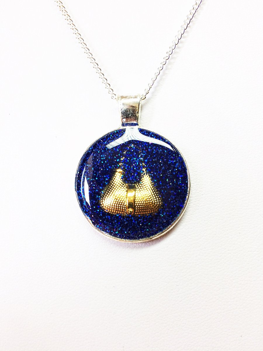 Feature Pendant Gold Colored Handbag on Blue Glitter Background
