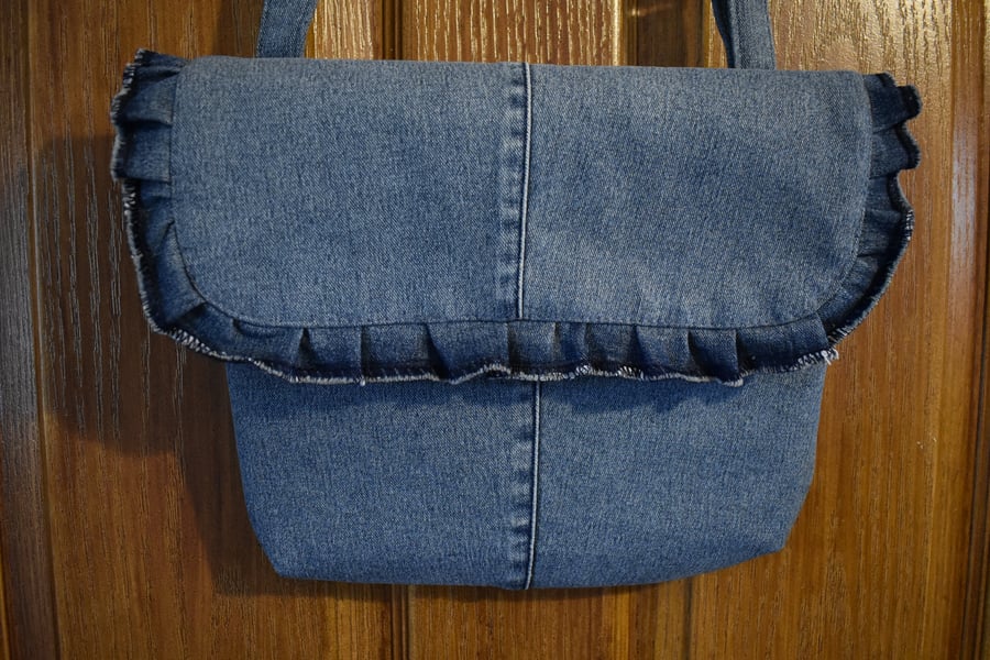 Repurposed blue denim handbag, shoulder or hand held strap length. Décor frill.