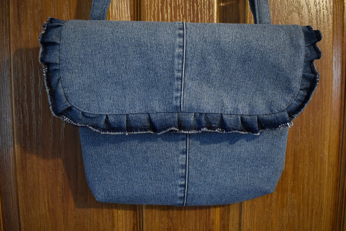 Repurposed blue denim handbag, shoulder or hand held strap length. Décor frill.