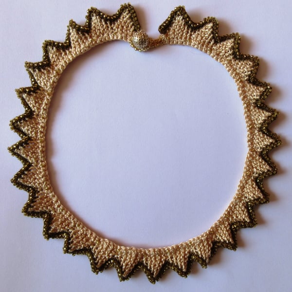 A knitted necklace with a crocheted, beaded edging in coffee and cream